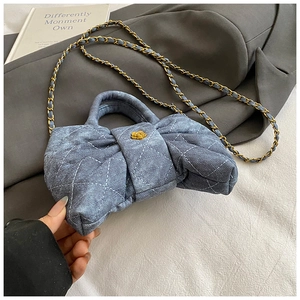 Détail d'un sac nœud en denim bleu matelassé avec boucle fleur dorée et bandoulière