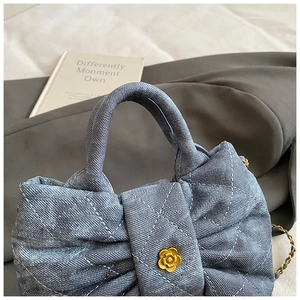 Détail du sac à main en jean matelassé avec boucle fleur dorée et bandoulière chaîne