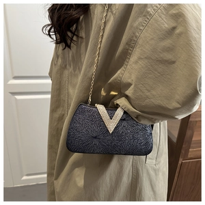 Detail of glitter evening box bag featuring a V-shaped rhinestone buckle and gold chain strap