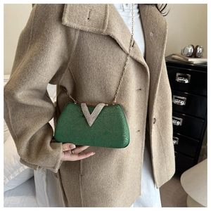 Detail of emerald green box clutch with gold crackle texture and silver V-shaped rhinestone
