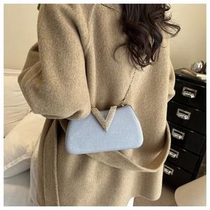 Light blue glitter evening bag with rhinestone V-shape buckle on camel wool coat