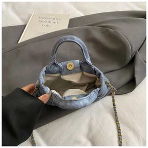 Détail du mini sac en denim bleu avec boucle magnétique dorée et doublure à chevrons