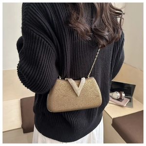 Close-up of sparkling gold evening clutch with V-shaped rhinestone buckle and chain