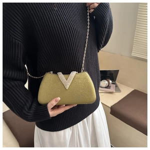 Macro shot of gold glitter box bag with V-shaped diamond buckle and elegant chain strap
