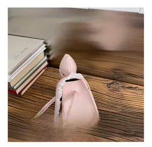 Pink girl's mini crossbody bag with white lace edges on a wooden table display