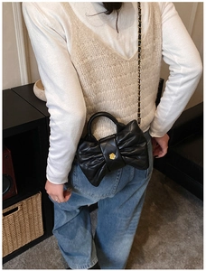 Vue arrière d'un mannequin portant le sac à main matelassé noir avec nœud et fleur dorée