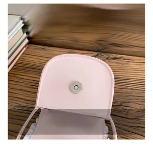 Close-up of pink mini bag showing magnetic buckle and white lace decorative border