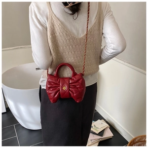 Vue mannequin d'un sac à main matelassé rouge avec nœud et boucle camélia dorée en détail