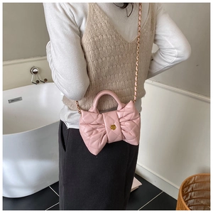 Détail du sac à main rose en forme de nœud avec texture matelassée et fermoir fleur dorée