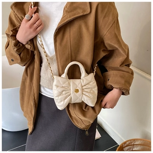 Détail du sac à main matelassé en forme de nœud crème avec logo camélia doré et chaîne