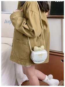 Detail of white mini crossbody bag featuring lace edges and yellow bow on girl model