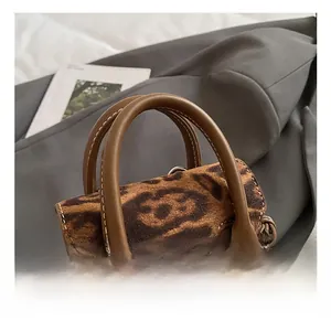 Detail der Leopard-Handtasche mit braunem Ledergriff und weißer Kontrastnaht im Fokus