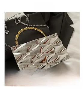Detail of silver acrylic clutch bag with geometric texture and golden beaded handle