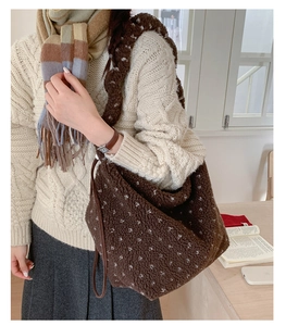 Détail du sac cabas en peluche marron à motifs cœurs porté avec une tenue d'automne