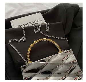 Detail of silver mirrored faceted clutch with gold bead handle and chain strap