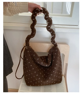 Détail du cabas en peluche marron à pois avec bandoulière ondulée sur une chaise