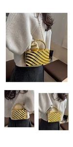 Detail of gold wavy metallic clutch bag with circular ring handle and chain strap