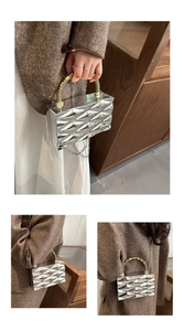Detail of silver geometric textured clutch with a gold bamboo handle and chain strap