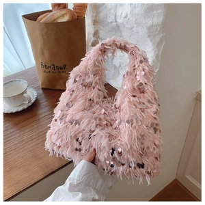 Pink faux fur bucket bag with sequins on a wooden table in a cozy indoor setting