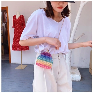 Rainbow beaded crossbody bag with gold chain strap shown on a model in a boutique