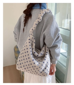 Gros plan du sac cabas en peluche crème avec étoiles bleues et bandoulière tressée