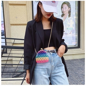 Close-up of a colorful acrylic beaded mini bag with a vintage gold chain strap