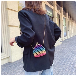 Detailed outdoor shot of a rainbow acrylic beaded mini crossbody bag with gold chain