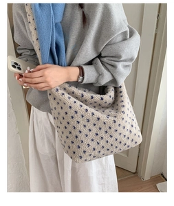 Gros plan d'un sac cabas en peluche crème avec étoiles bleues porté par un mannequin