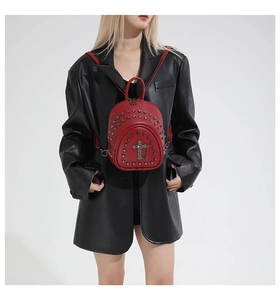 Vue détaillée du sac à dos rouge en cuir avec clous métalliques et pendentif croix gothique