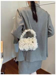 Close-up of a white faux feather bucket bag with gold sequins and silver chain strap