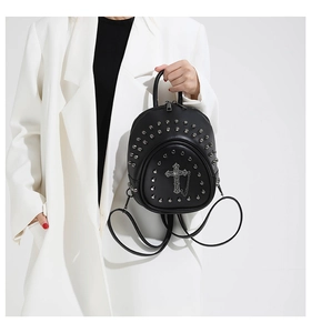 Détail d'un mini sac à dos noir avec clous argentés et pendentif croix gothique