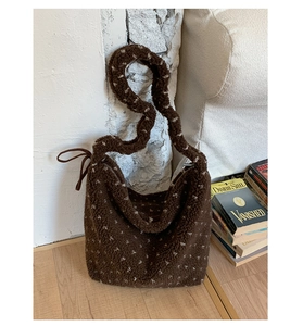 Détail du sac fourre-tout en peluche marron à pois avec bandoulière sur sol en bois