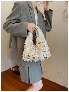 Detail of elegant sequin faux fur handbag in beige, featuring gold chain and bucket style
