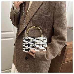 Detail of silver acrylic box bag with diamond pattern, bamboo handle and chain strap