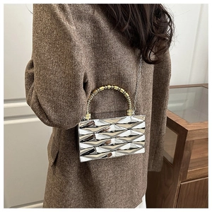 Detail of silver acrylic clutch bag with 3D geometric texture and gold handle