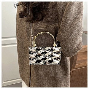Detailed shot of silver acrylic clutch with geometric facets and a gold bead handle