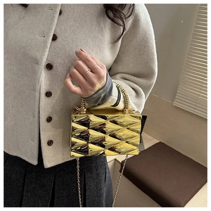 Detail of a gold metallic geometric clutch with a unique spring handle and chain strap