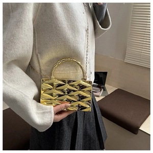 Detail shot of golden acrylic box clutch featuring embossed rhombic patterns and chain strap