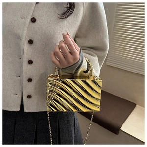 Detail of gold acrylic evening clutch featuring unique wavy texture and metallic ring handle