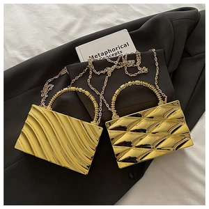 Detail of gold evening clutches with ripple and geometric textures on a dark blazer