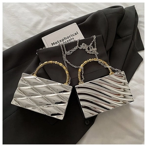 Detail of silver acrylic clutch bags with wave texture and gold beaded handle