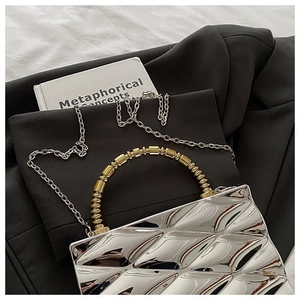 Detail of silver geometric patterned bag with golden beaded handle on black blazer