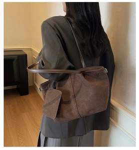 Detail of dark brown suede tote bag featuring a matching small pouch on a long shoulder strap