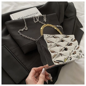 Close-up of silver mirror acrylic clutch bag with geometric texture and gold bead handle