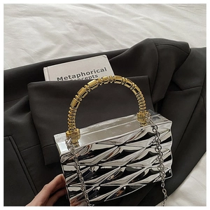 Close-up of silver geometric textured evening clutch with gold bead handle and chain strap