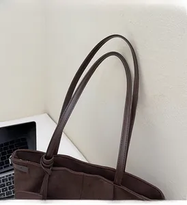 Detail of sturdy faux leather handles on a large dark brown faux suede tote bag