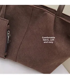 Close-up of soft brown suede tote bag showing fabric texture and side zipper pocket