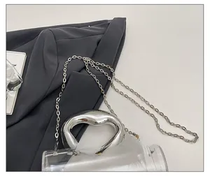 Détail du sac cylindrique transparent en acrylique avec poignée et bandoulière en argent