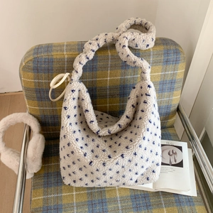 Sac cabas en polaire pelucheuse blanche à pois bleus posé sur un fauteuil cosy