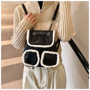 Detalle de mochila de cuero negro con ribete de piel sintética blanca y correas de cadena